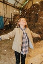 Ginger girl standing under shower of wooden shawings she threw inside barn