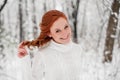 Ginger girl in white sweater in winter forest. Snow december in park. Christmas time. Royalty Free Stock Photo