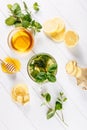 Ginger green tea in a glass for flu cold winter days. Side view on white wooden background decorated with mint, lemon Royalty Free Stock Photo