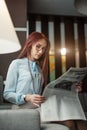 Happy young businesswoman reading newspaper in hotel lobby Royalty Free Stock Photo