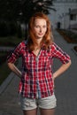 Ginger haired women in jeans shorts and red shirt posing outdoors. Royalty Free Stock Photo