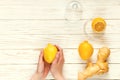 Ginger-lemon in hands on white wooden background, prevention of colds. Selective focus