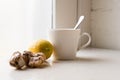 Ginger, lemon and white cup next to window