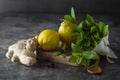 Ginger, lemons and mint leaves on dark background. Ginger tea, drink ingredients, cold and autumn time