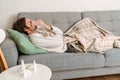 Ginger man feeling sick and sneezing while lying on couch Royalty Free Stock Photo