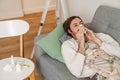 Ginger man feeling sick and sneezing while lying on couch Royalty Free Stock Photo