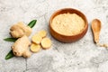 Ginger powder in a wooden bowl and a ginger root on a stone background Royalty Free Stock Photo