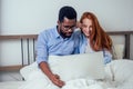 Ginger redhaired european female and handsome afro african male together hugging lying in bedroom at home cozy apartment Royalty Free Stock Photo