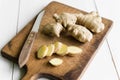 Ginger root sliced on old cutting board and white table Royalty Free Stock Photo