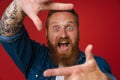 Ginger shocked man with tattoo making frame gesture Royalty Free Stock Photo