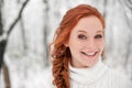 Ginger smiling girl in white sweater in winter forest. Snow december in park. Portrait. Christmas cute time. Royalty Free Stock Photo