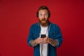 Ginger surprise man in headphones listening music and using cellphone