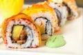 Ginger sushi rolls with decorations served on a white flat tray