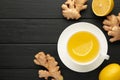 Ginger tea with lemon in a white cup on blakc wooden background