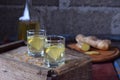 Ginger tincture or ale on wooden background. Spice yellow liqueur in a glass. Homemade Alcohol drink. Rustic style.