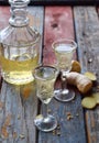 Ginger tincture or ale on wooden background. Spice yellow liqueur in a glass. Homemade Alcohol drink. Rustic style