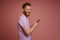 Ginger white man with beard smiling and using mobile phone Royalty Free Stock Photo