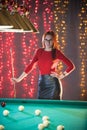 A ginger woman in black skirt standing in billiard club holding a cue Royalty Free Stock Photo