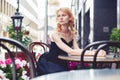 Ginger woman sitting in outdoor cafe, photo toned