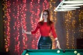 A ginger woman standing in billiard club holding a cue Royalty Free Stock Photo
