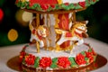Gingerbread carousel in front of defocused lights of Chrismtas decorated fir tree. Holiday sweets. New Year and Christmas theme. F