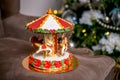 Gingerbread carousel in front of defocused lights of Chrismtas decorated fir tree. Holiday sweets. New Year and Christmas theme. F