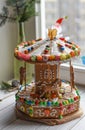 A gingerbread carousel and some Christmas decoration elements on a white wooden surface
