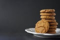 A gingerbread cookie leans against a stack of cookies on a white plate with a black background with copy space Royalty Free Stock Photo