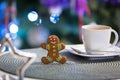 Gingerbread cookie man at the cup of hot coffee and christmas tree lights in background Royalty Free Stock Photo