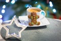 Gingerbread cookie man at the cup of hot coffee and christmas tree lights in background Royalty Free Stock Photo