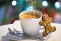 Gingerbread cookie man at the cup of hot coffee and christmas tree lights in background Royalty Free Stock Photo