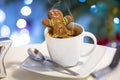 Gingerbread cookie man takes a bath in the cup of hot coffee with christmas background