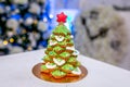 Gingerbread fir tree in front of defocused lights of Chrismtas decorated living room. Holiday sweets. New Year and Christmas theme