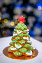 Gingerbread fir tree in front of defocused lights of Chrismtas decorated living room. Holiday sweets. New Year and Christmas theme