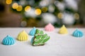 Gingerbread fir tree and meringue on the table in front of defocused lights of Christmas decorated fir tree. Holiday sweets. New Y