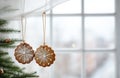 Gingerbread gingerbread hanging from a string as Christmas decorations against a blurred window background. AI-Generated