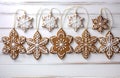 Gingerbread gingerbread hanging from a string as Christmas decorations on a white wooden background. AI-Generated