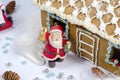 Gingerbread house decorated with glaze on a light background. Holiday decorations. Santa Claus figurine