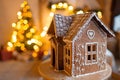 Gingerbread house over defocused lights of Chrismtas decorated fir tree Royalty Free Stock Photo