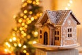 Gingerbread house over defocused lights of Chrismtas decorated fir tree Royalty Free Stock Photo