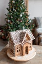 Gingerbread house over defocused lights of Chrismtas decorated fir tree Royalty Free Stock Photo