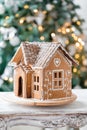 Gingerbread house over defocused lights of Chrismtas decorated fir tree Royalty Free Stock Photo
