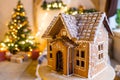 Gingerbread house over defocused lights of Chrismtas decorated fir tree Royalty Free Stock Photo