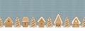 Gingerbread houses and fir trees on light blue knitted background. Gingerbread village. Seamless border. Christmas background Royalty Free Stock Photo