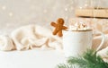 Gingerbread man cookie in cup of hot cocoa or coffee with marshmallow, fir tree, gifts and warm cozy sweater. Christmas Royalty Free Stock Photo