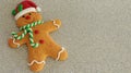 Gingerbread man with red Santa hat green and white scarf on a silver background with writing space