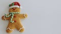 Gingerbread man with red Santa hat green and white scarf on a white background with writing space