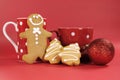Gingerbread man with red polka dot coffee mug and tea cup with Christmas tree shape cookies