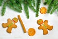 Gingerbread mans and Christmas tree branches on wooden backgroun