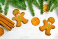 Gingerbread mans and Christmas tree branches on wooden background